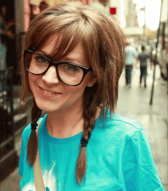 a girl wearing glasses and a blue shirt is smiling