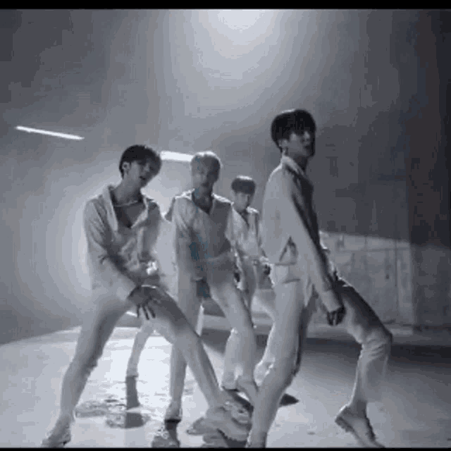 a group of men in white shirts and pants are dancing in a black and white photo .