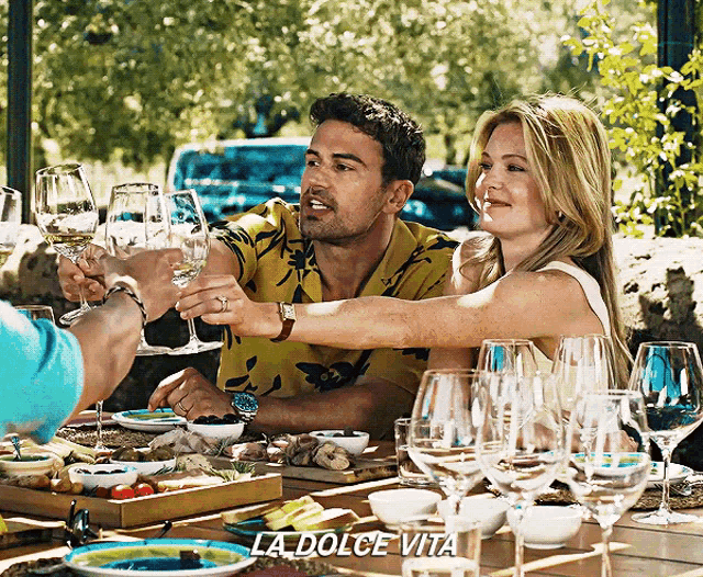 a man and a woman toasting with wine glasses with the words la dolce vita written on the bottom