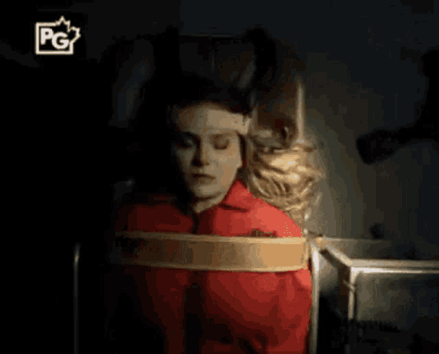 a woman is tied up in a chair with a pg logo on the bottom