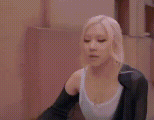 a woman in a white tank top and a black jacket is dancing in a room .