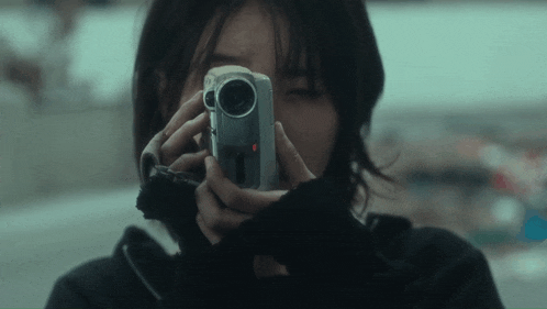 a woman is taking a picture with a camera that has the letter r on the lens