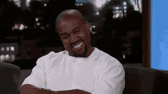 a man with a beard is sitting on a couch and smiling .