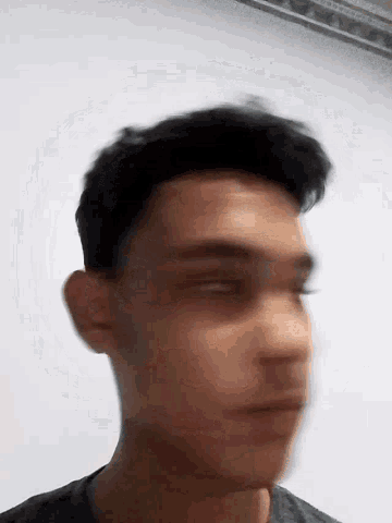 a close up of a man 's face with his eyes closed against a white wall .
