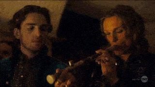 a man is smoking a cigarette in a dark room with a candle in his hand .