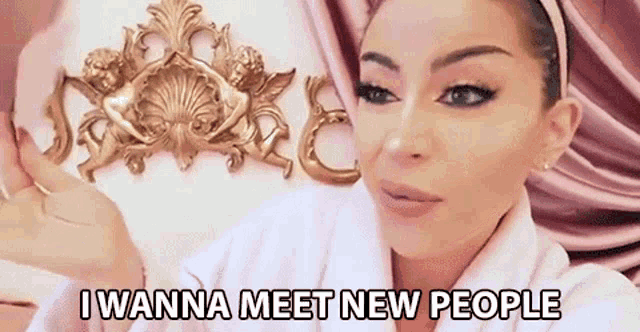 a woman in a bathrobe is sitting in front of a wall with angels on it and says i wanna meet new people .
