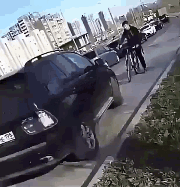 a man is riding a bike down a sidewalk next to a car with license plate number x492