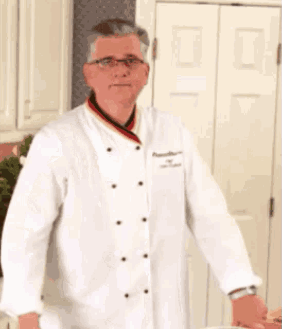 a man in a chef 's coat is giving a thumbs up sign