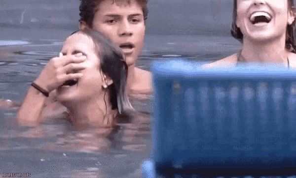 a group of people are swimming in a pool and one of them is covering her eyes with her hand