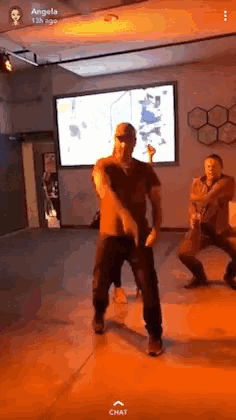 a man is dancing in front of a screen that says angela on it