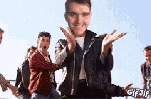 a group of men are standing around a man in a leather jacket with his hands outstretched