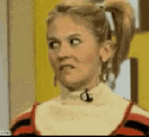a woman with a ponytail and a microphone around her neck is making a funny face