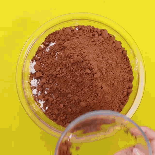 a person is pouring cocoa powder into a bowl
