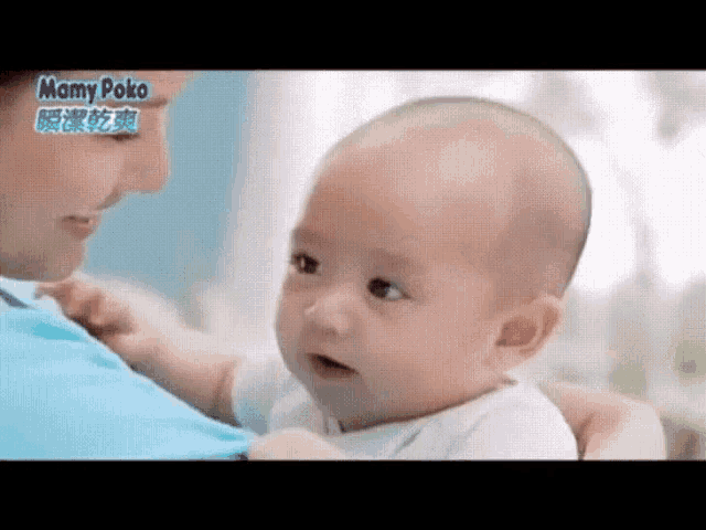 a woman is holding a baby in her arms and the baby is making a face .