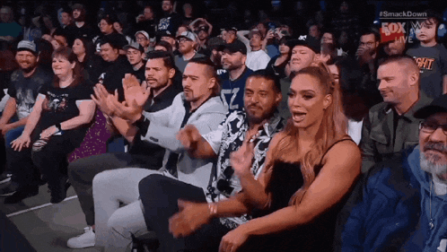a group of people are sitting in a stadium watching a wrestling match sponsored by fox