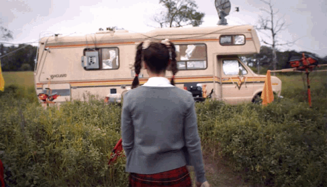 a girl in a plaid skirt is standing in front of a rv that says spaceland