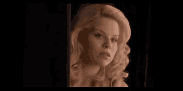 a man and a woman are standing next to each other in a dark room looking at something .