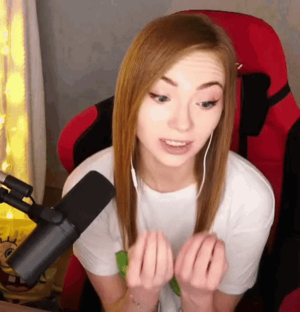 a young woman is sitting in a red chair in front of a microphone and wearing headphones .