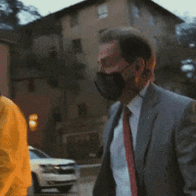 a man in a suit and tie with a mask on his face