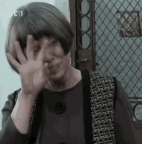 a woman is covering her face with her hand and waving her hand .