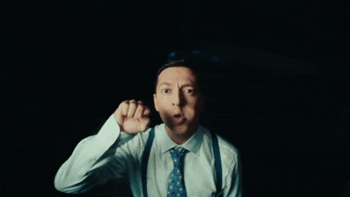 a man in a white shirt and blue tie is making a face