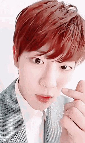 a young man with red hair is making a heart shape with his hand