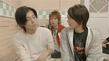 three young men are sitting next to each other in a room with a door that says sars on it .