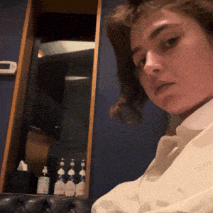 a woman in a white shirt is sitting in front of a bottle of lotion
