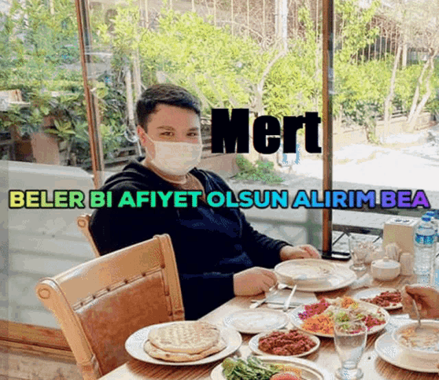 a boy wearing a mask sits at a table with plates of food and the name mert written on the bottom