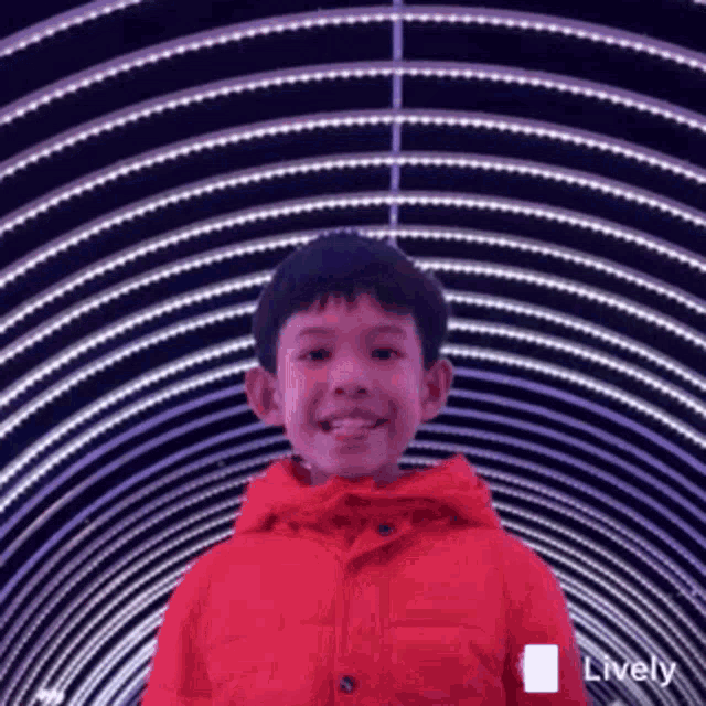 a young boy wearing a red jacket is smiling in front of a tunnel of lights