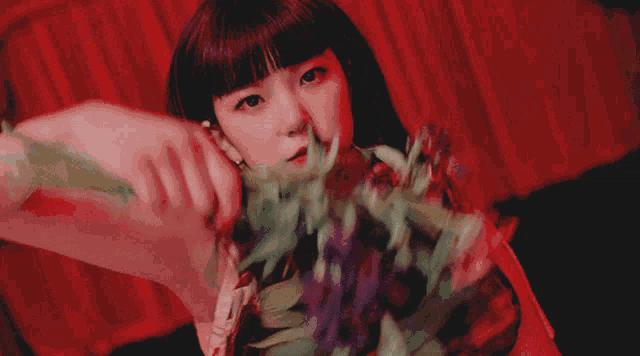 a close up of a woman 's face with flowers behind her