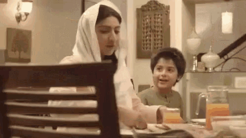 a woman and a child are sitting at a table in a kitchen .