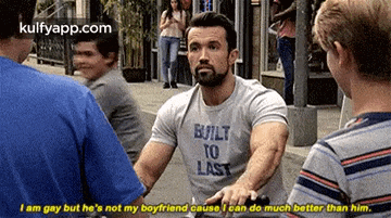 a man wearing a t-shirt that says `` built to last '' is talking to another man .