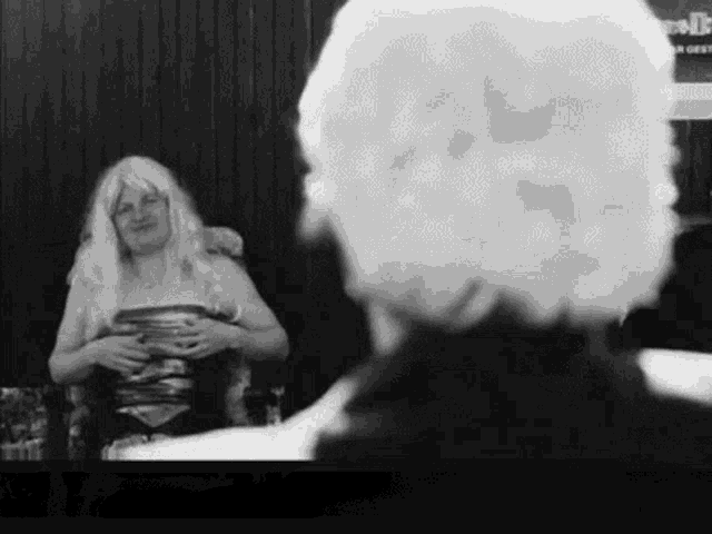 a black and white photo of a woman in a wig looking at a man .