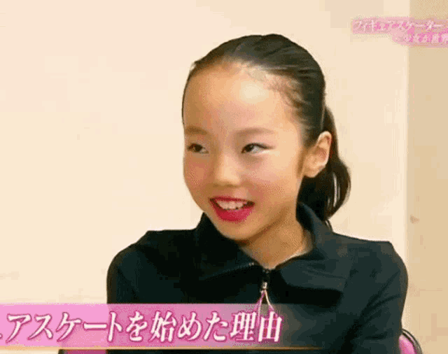 a young girl wearing a black jacket and red lipstick is smiling in a video .