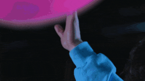a person in a blue sweater holds their hand up