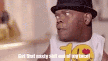 a man wearing a hat and a bib with the words `` get that nasty shot at my face '' written on it .