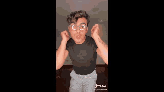 a man wearing glasses and a black shirt has a tiktok sticker on his chest