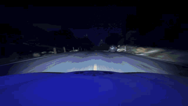 a car is driving down a road at night and the hood of the car says police