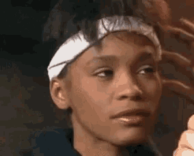 a close up of a woman wearing a headband and looking at herself in a mirror .