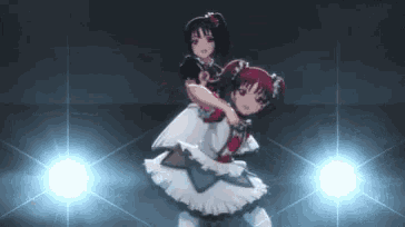 a couple of anime girls are dancing in front of a spotlight