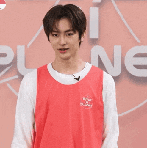 a young man wearing a red vest that says boys planet