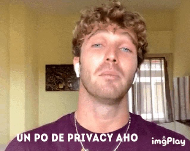 a man with curly hair is wearing ear buds and a purple shirt with the words " un po de privacy aho " on it