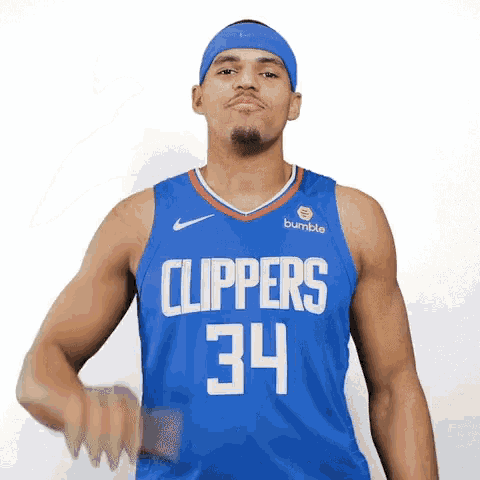 a basketball player wearing a blue jersey with the number 34 on it is standing in front of a white background .