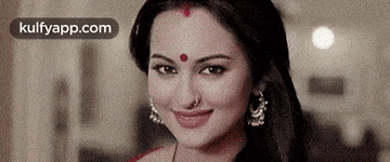 a close up of a woman with a red dot on her forehead smiling .