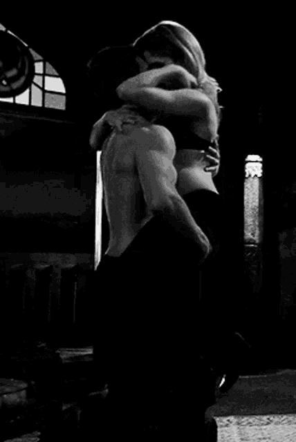 a black and white photo of a man and woman kissing .