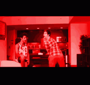 a man in a plaid shirt stands next to another man in a tank top