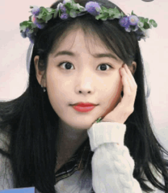 a woman with a flower crown on her head looks at the camera