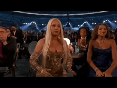 a woman in a gold dress is standing in a crowd