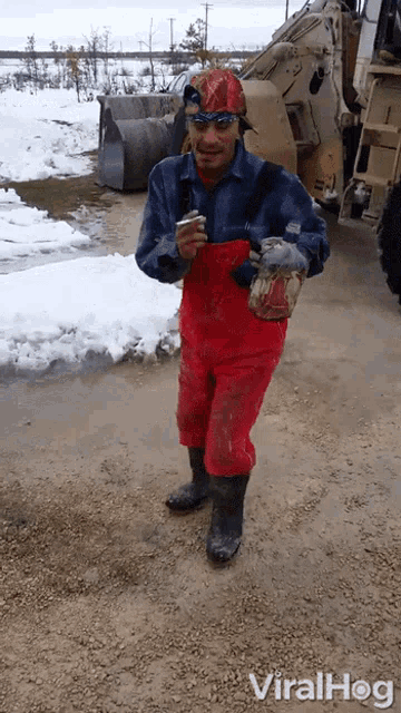 a man wearing red overalls and a red hat is standing in front of a snowy field with the words viralhog written below him
